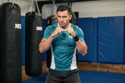 Combattant d'arts martiaux mixtes en position de combat dans une salle d'entraînement moderne, illustrant une confrontation de puissance entre deux adversaires redoutables
