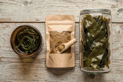 Comparaison de trois formes de compléments à base de goémon et algues : extrait fermenté en bouteille ambrée, poudre de dulse et algues séchées entières sur bois clair